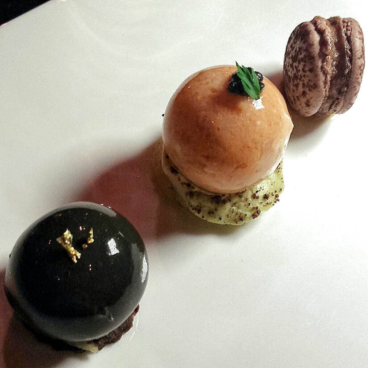 Macaron alle fave di cacao e finanziera - Sfera di grancevola, piselli e grue - Raviolo di tartufo, sablé al cacao